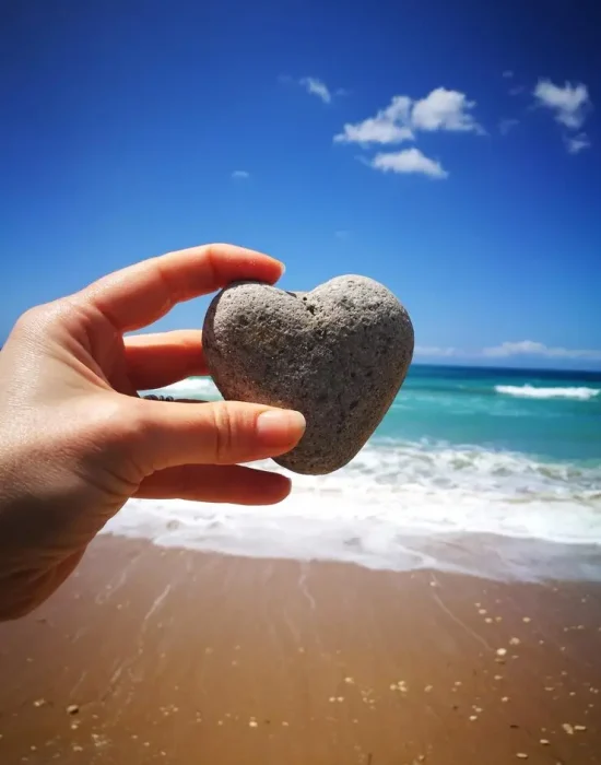 midsection-person-holding-heart-shape-beach_1048944-335052